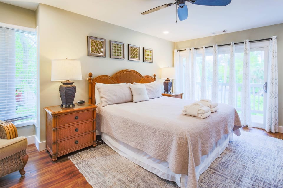 The master suite features a king bed, night stands with reading lamps and sliding door access to the exterior balcony.