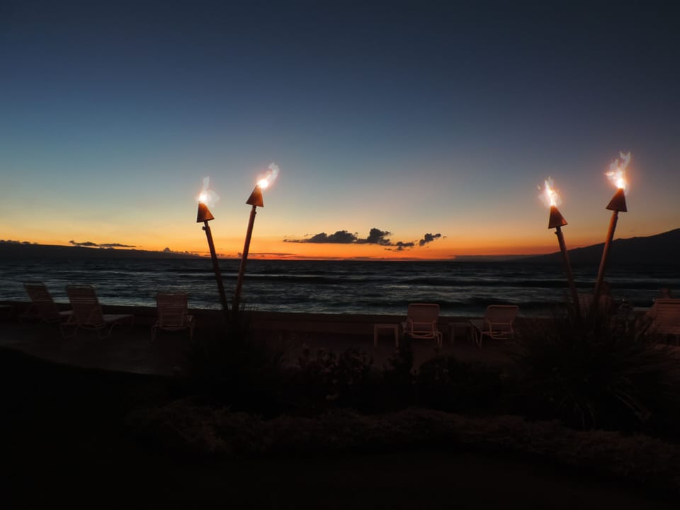 Tiki torches at sunset add to the Hawaiian ambiance