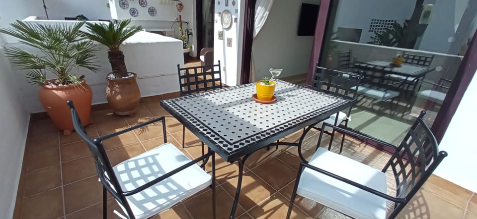 Large sunny terrace with overhead sun blind, table, chairs and mountain views.