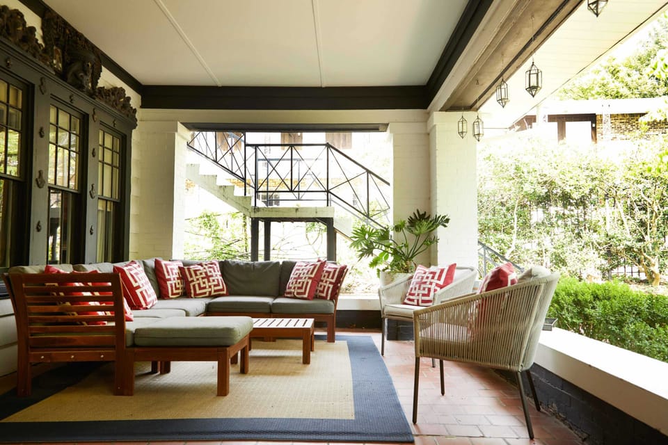 The front porch features a large sectional sofa. It is a wonderful place to gather or to sit and enjoy the front gardens.