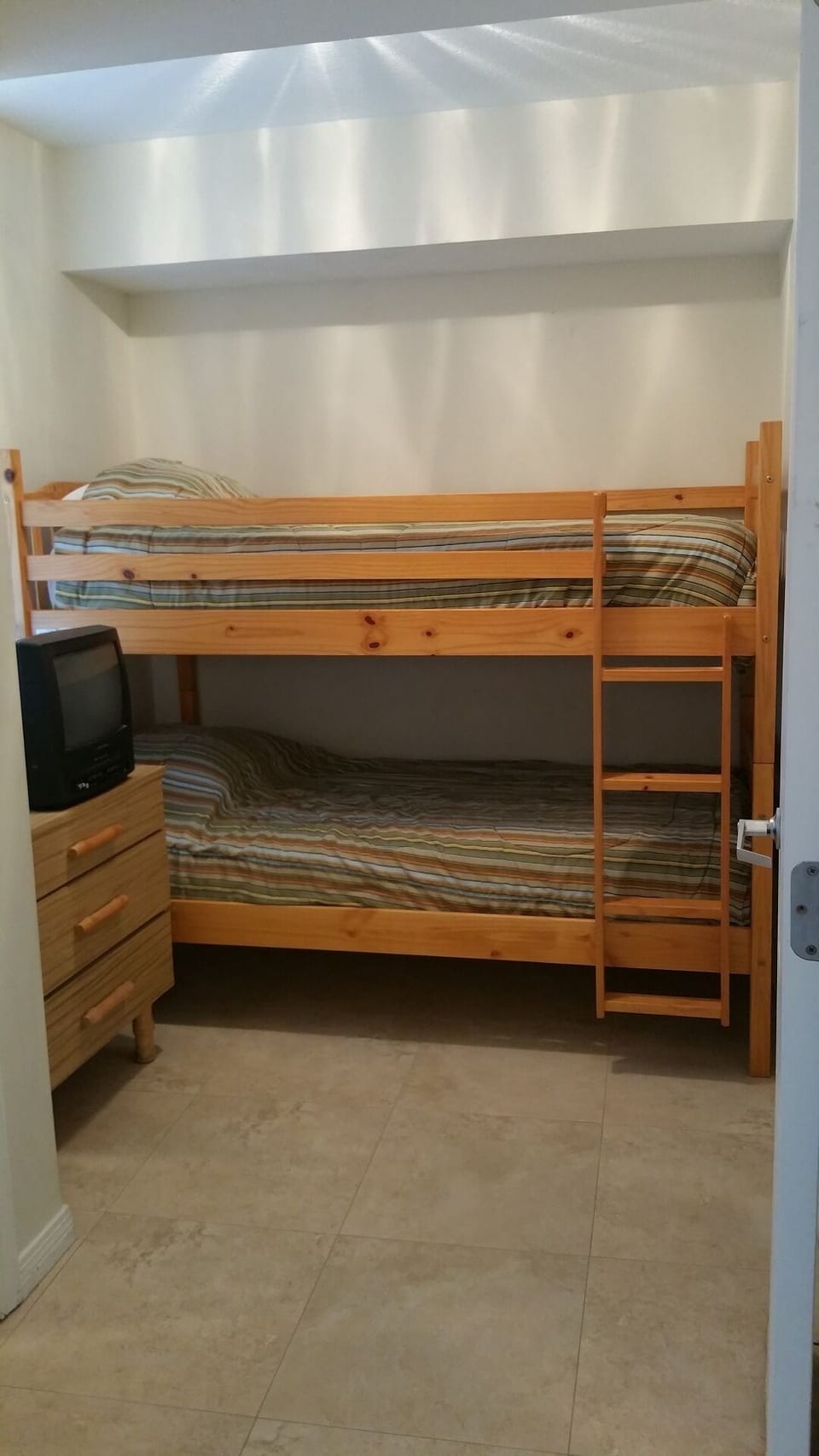 3rd bedroom/Bunkroom with dresser and closet access. TV on dresser