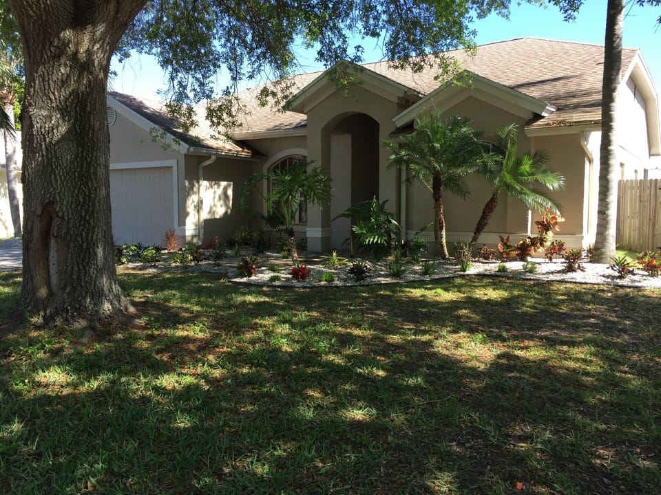 Paradise Retreat Front of home with tropical plantings, 2 car garage fenced yard
