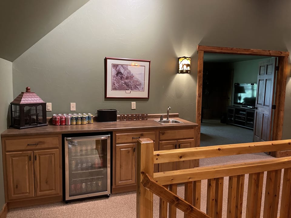 Convenient beverage cooler with wet bar next to pool, poker table and media room