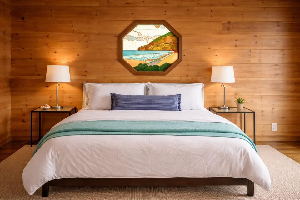 Peaceful oceanview master bedroom featuring a king bed and beautiful coastal stained-glass window