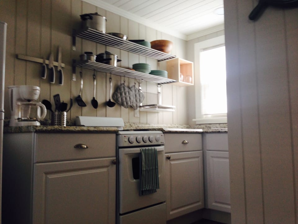 Kitchen stocked with pots & pans, dishware, coffee pot, microwave & utensils