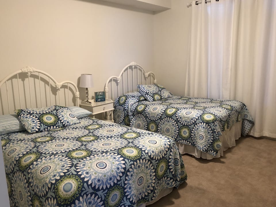 The large  guest bedroom with two full size beds. There is a flat screen tv.