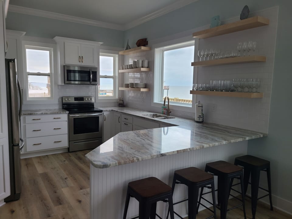 View of kitchen, granite counters.  Ice maker in fridge. Bar seating for 4.