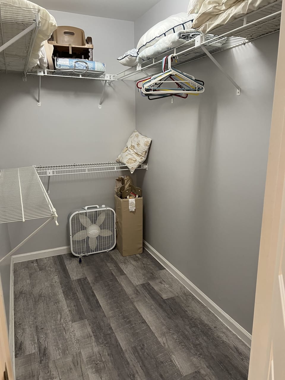 Master bedroom walk in closet storing a pack n play & baby high chair type seat.
