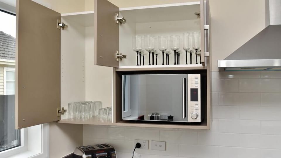 Microwave and glasses, alongside the oven and hob.