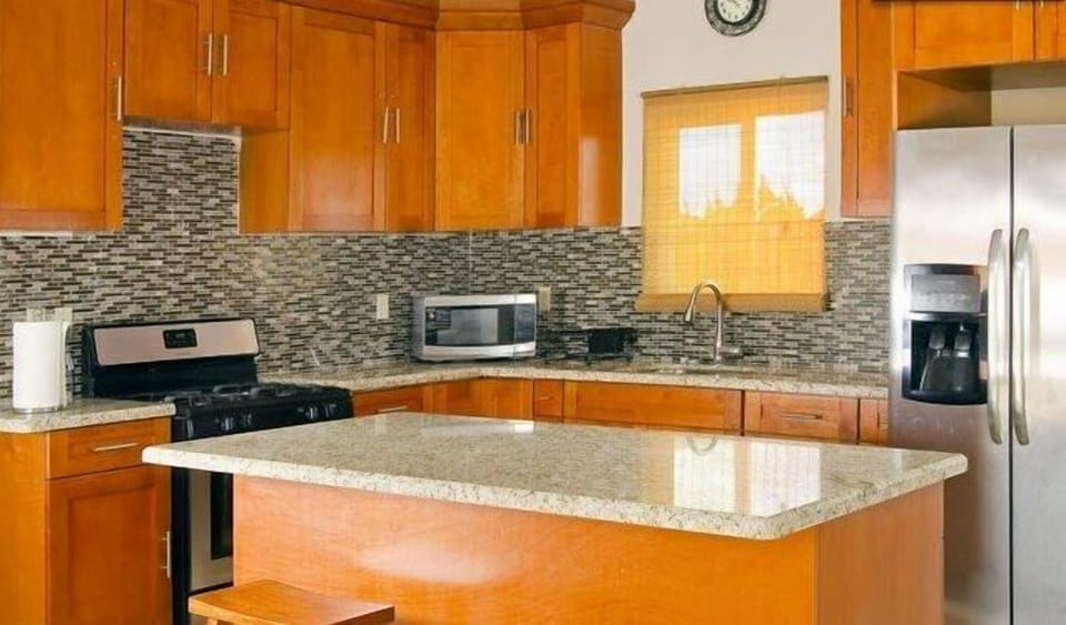 KITCHEN WITH REAL WOOD CHESTNUT STAINED CABINETS AND MOSAIC BACKSPLASH