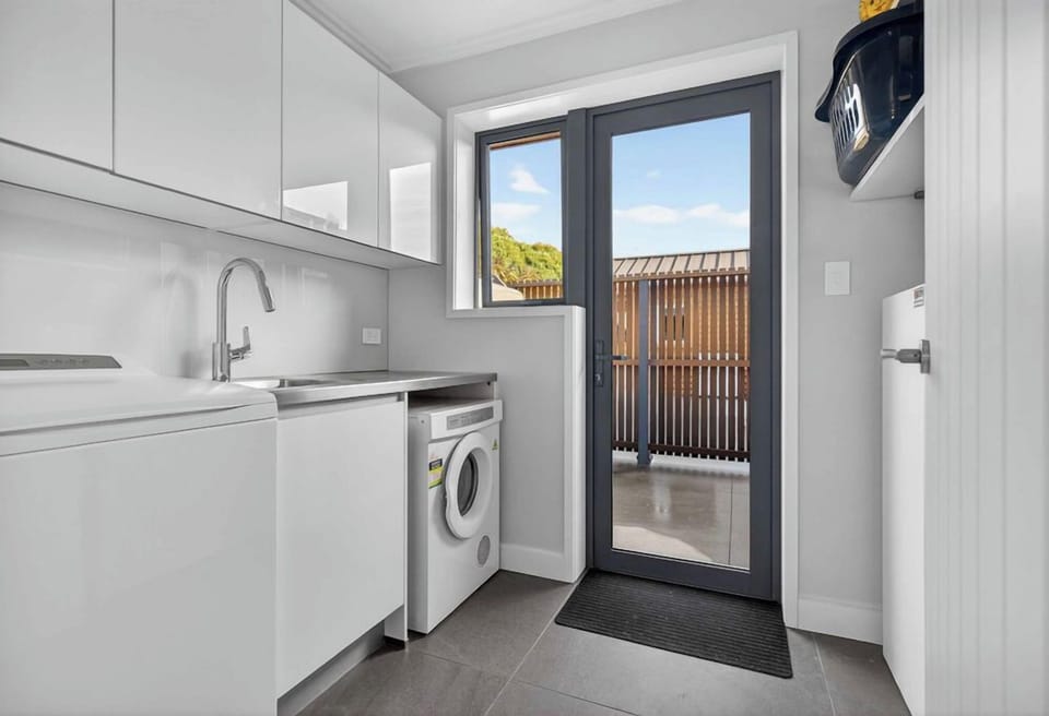 Full laundry room with washer, dryer, iron + board and clothes rail
