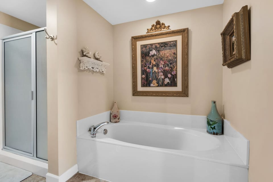 Walk-in shower, bath tub and original artwork in master bathroom. 