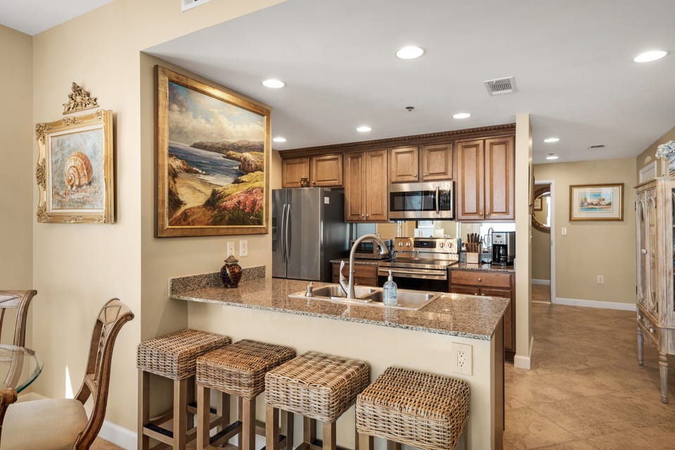 View of kitchen  from dining room showing eating bar with four seats for guests.