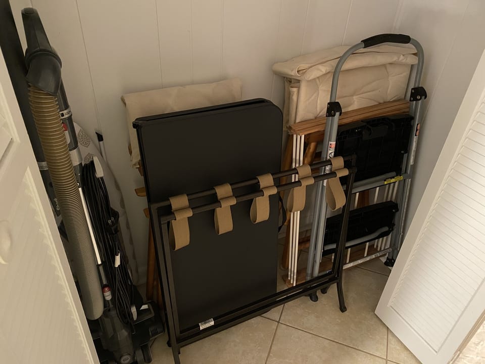 Closet contains extra chairs, game/card table, clothes rack, and luggage rack.