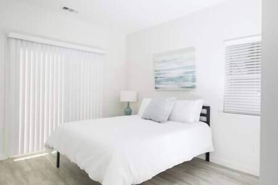 Bedroom 1 with sliding door to shared patio, offering peaceful views of olive orchard and trees.