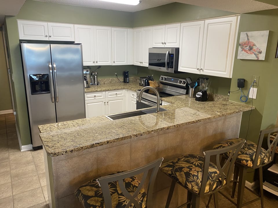 Fully equipped kitchen with new appliances and bar seating.