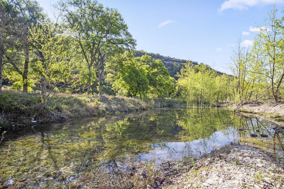 Peaceful creekside retreat with crystal-clear water and lush hill country views-perfect for relaxing or exploring nature.