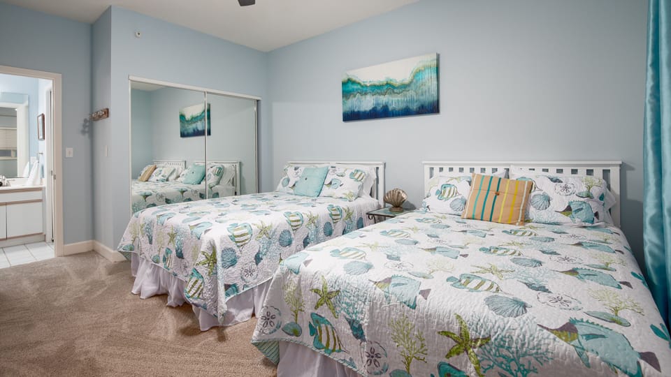 Third bedroom with two queen beds and view into bathroom.