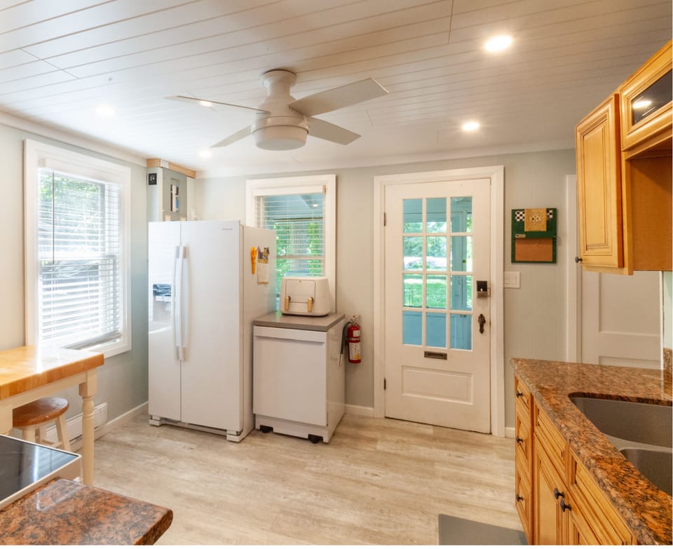 Kitchen showing fridge, dishwasher, air-fryer and door to screened porch.