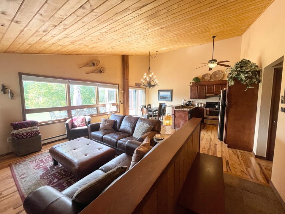 Great room with vaulted ceiling, leather sofas, dining & kitchen; deck access.