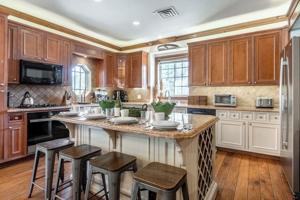 Warm wood finishes, a large island with seating, and abundant natural light create an inviting space in the well-eqipped kitchen.