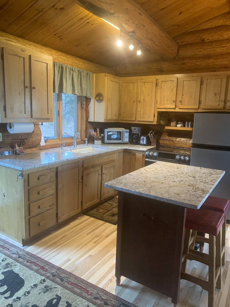 Kitchen with island, fridge, stove, microwave, and coffee maker.