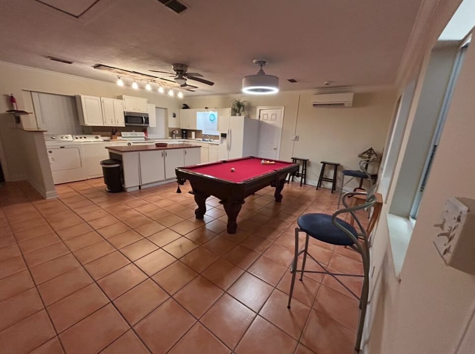 View of kitchen with open room and pool table when walking in from media room