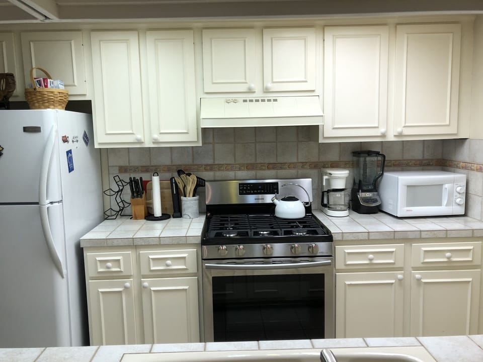 The kitchen is fully stocked with appliances, dishes, pots and pans.