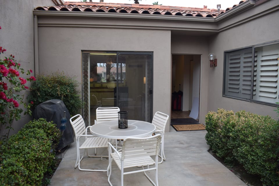 Front door to the right and slider to the left as well as a gas barbeque & table