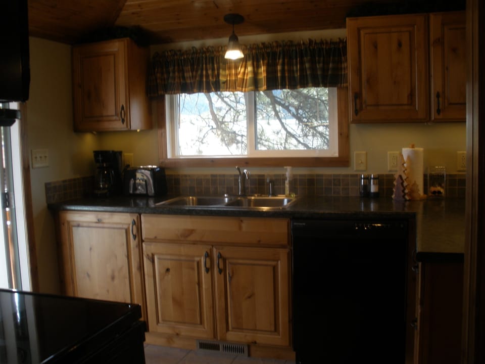 The fully equipped kitchen with knotty alder cabinets & a wonderful window view 