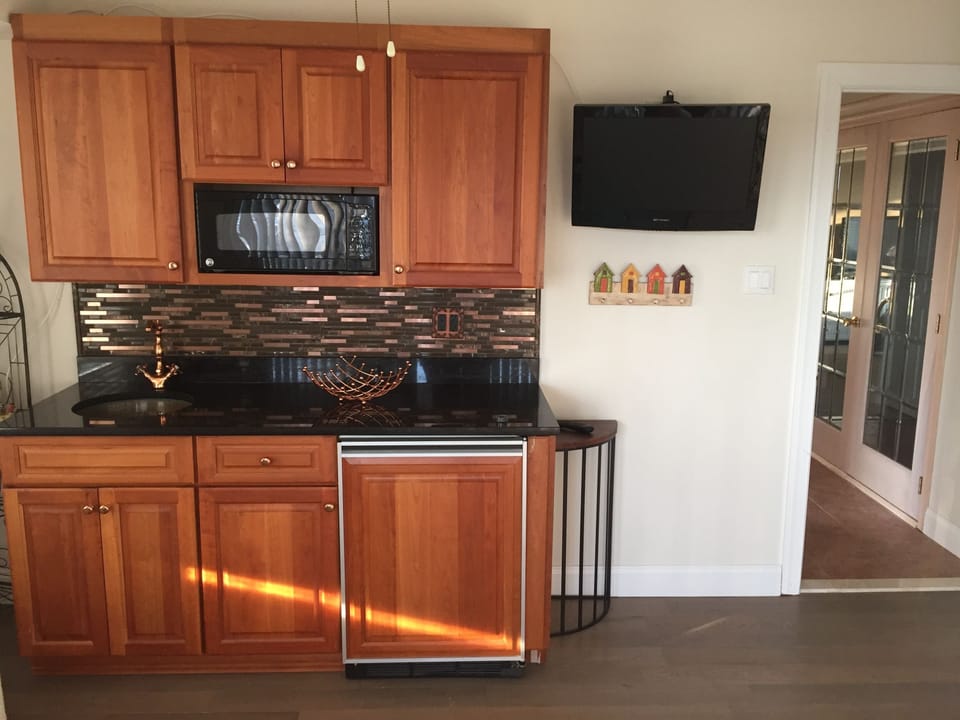 Kitchen has coffee pot, toaster, induction stove top with pots and microwave. 