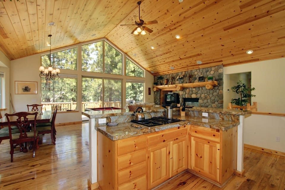 Great room w/ vaulted pine ceilings, large windows & river rock fireplace