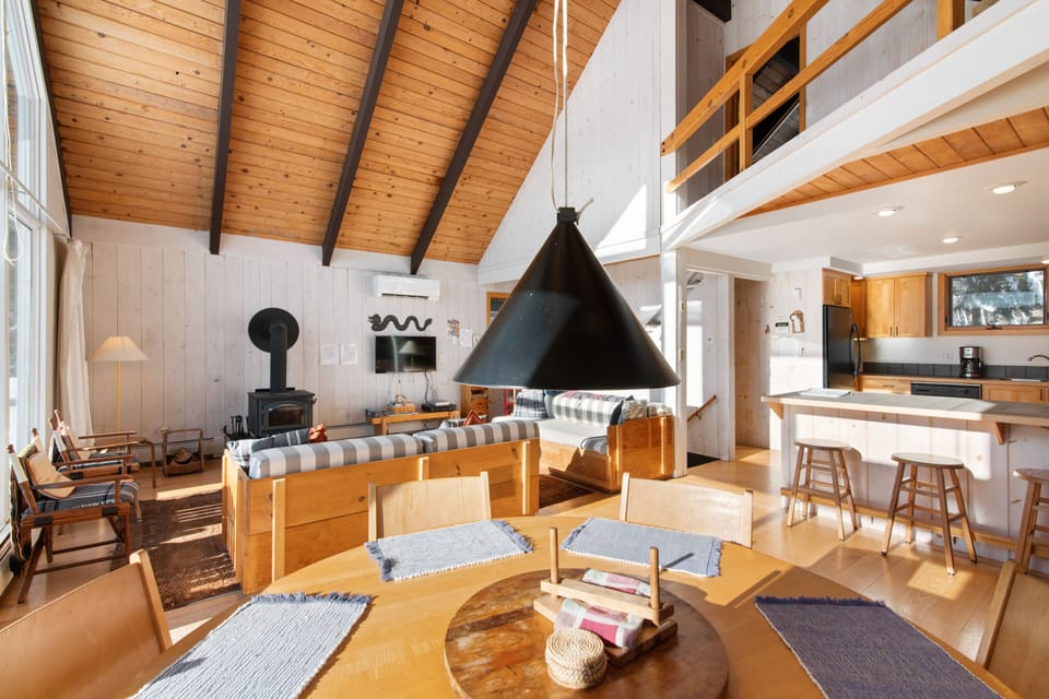 This shows wood stove, TV, the eat-in counter, and dining table...