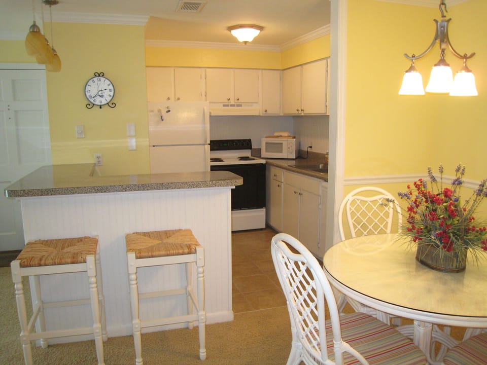 Breakfast bar with pendant lighting overlooks kitchen and dining area.
