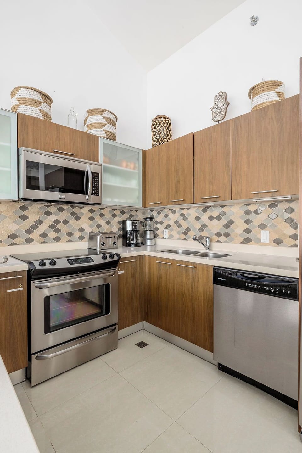 This fully equipped kitchen features sleek stainless steel appliances, beautiful tile backsplash, and warm wood cabinetry—everything you need to prepare meals during your stay.