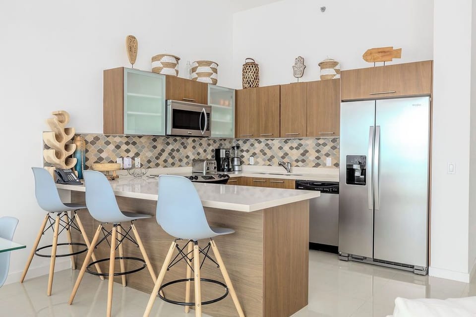 Step into your modern open kitchen featuring warm wood cabinetry, stainless appliances, and a sleek breakfast bar where you'll gather for meals and conversation.