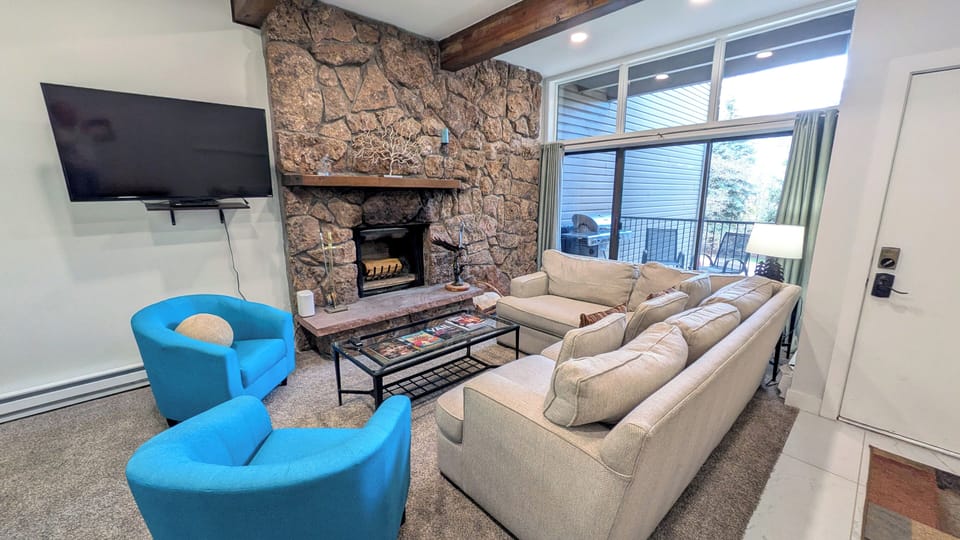 BC West Condo #12 Living room w/ wood fireplace and balcony w/ propane BBQ grill