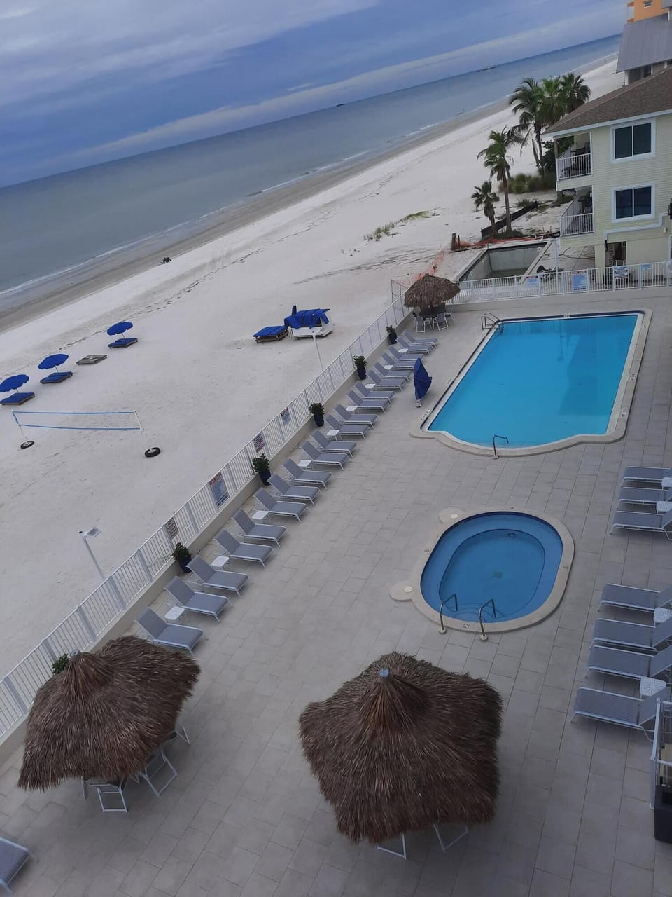 Large beachside pool and hot tub with tiki huts