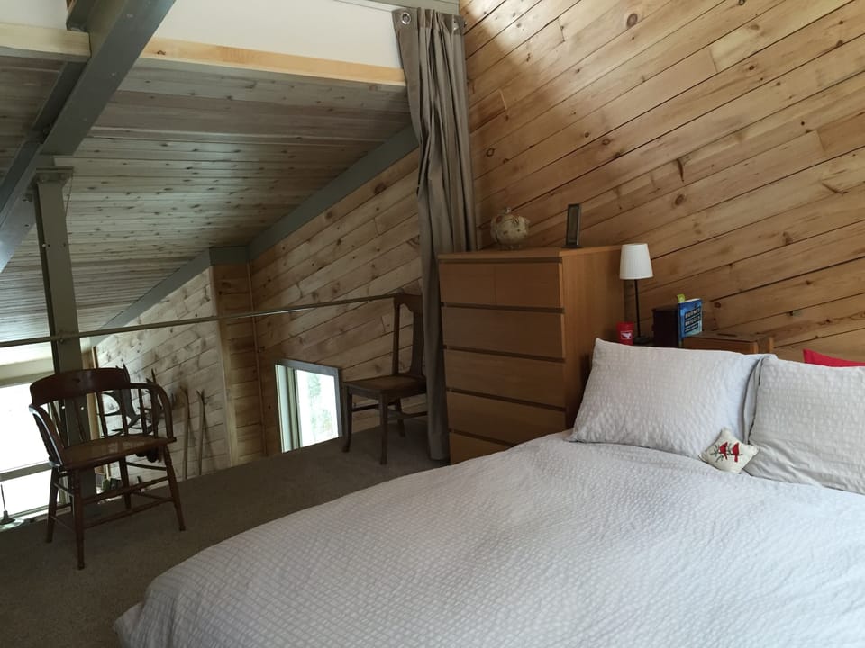 North loft bedroom overlooking living area and deck. Curtains provide privacy.