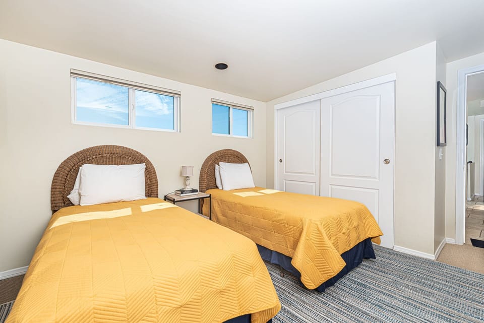 Rear third level bedroom hosts 2 Twin beds, carpeting, closet, and sliding glass door that leads out to large deck with seating.
                