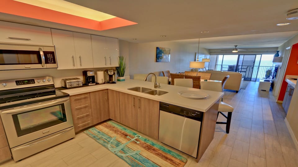 Stainless steel appliances and white quartz countertops. Fully stocked kitchen.