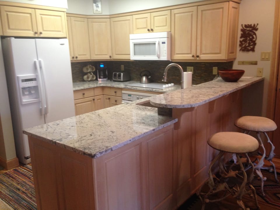 Granite countertops, and full kitchen with two barstools