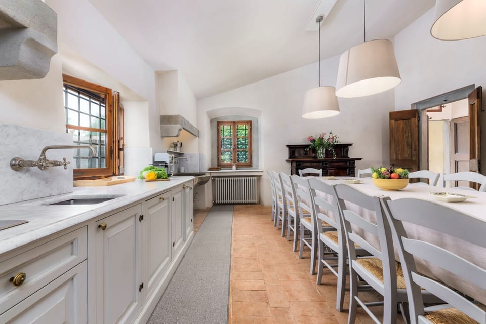 Updated picture of the kitchen, showing a larger dining table to comfortably accommodate 16 people (June 2024)