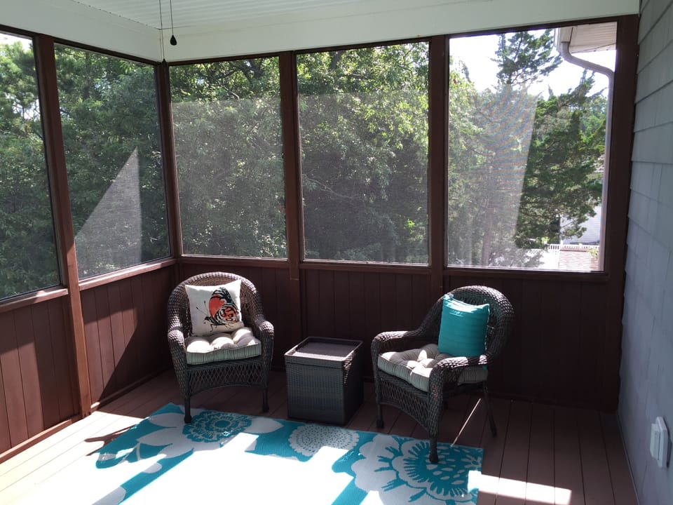 Top level screened porch with seating, sunset/bay views