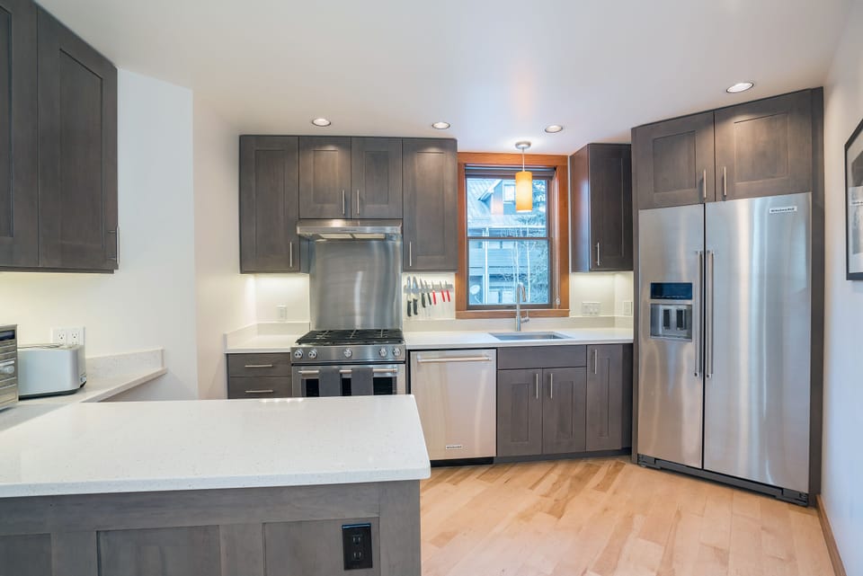 Fully-equipped modern kitchen with stainless appliances, gas range & vent hood