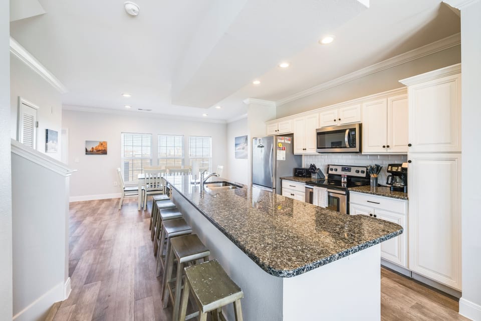 Your spacious kitchen boasts granite countertops, stainless steel appliances, and a breakfast bar perfect for morning coffee or casual dining.