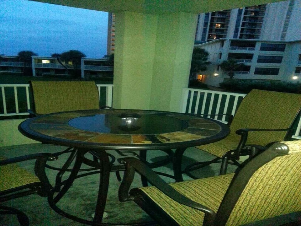 Balcony overlooks beach with beautiful view on bar height stools. 