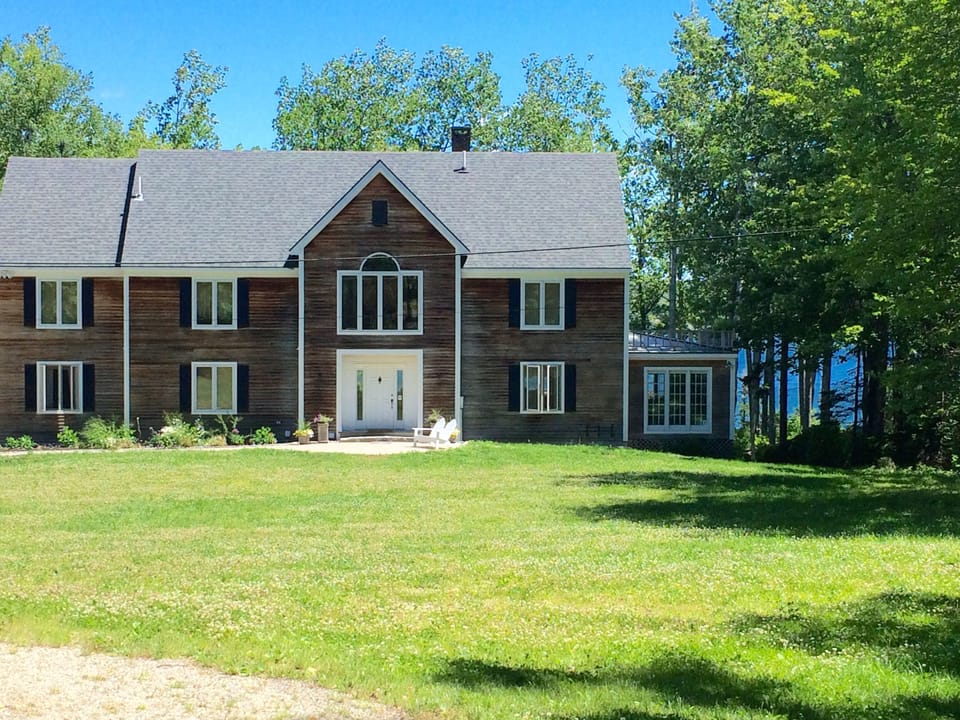 Front view of home with expansive yard and glimpse of beautiful bay in back.
