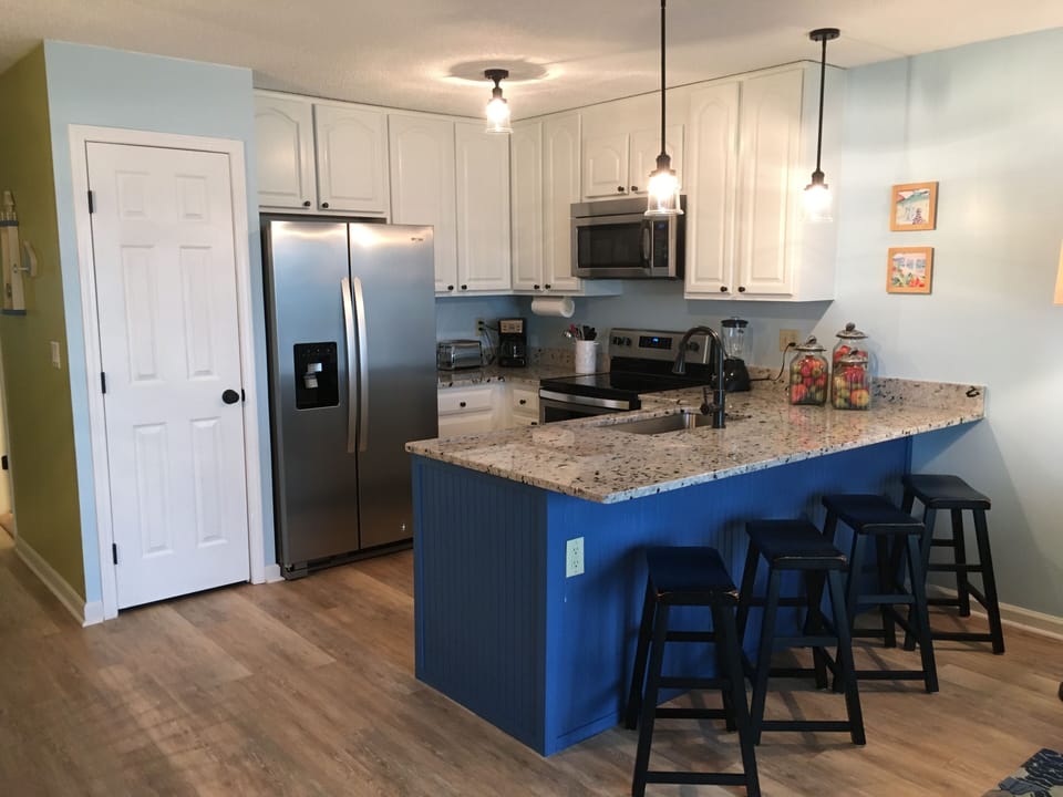 Updated and open kitchen concept with pendant lighting over bar area