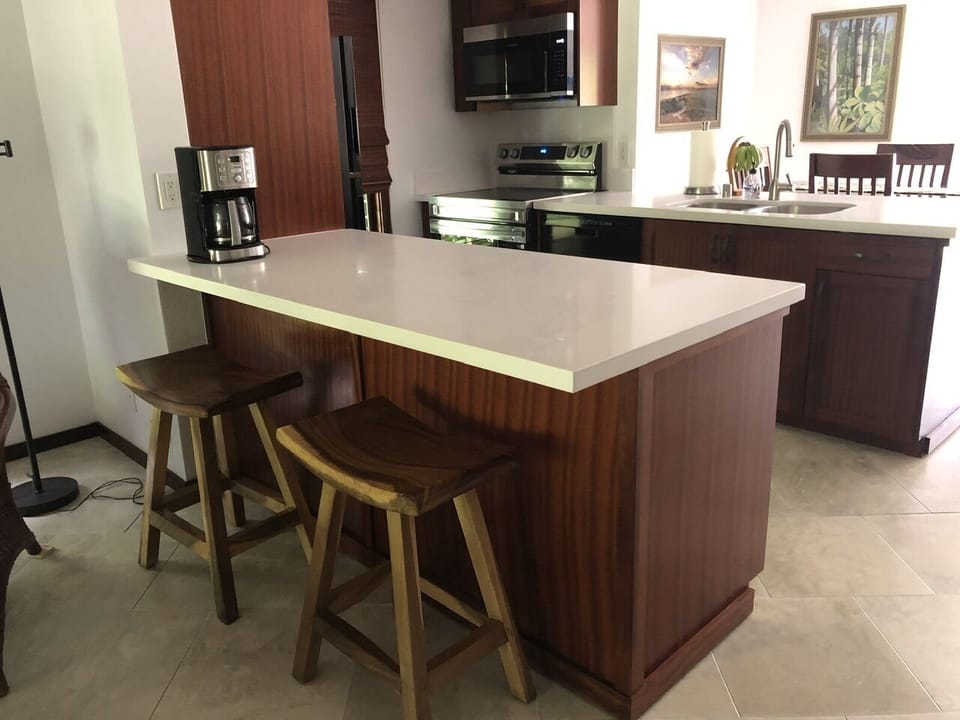 two quartz islands kitchen, counter stools, microwave and stove.